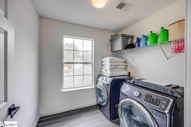 laundry room with wood-type flooring, a textured ceiling, and separate washer and dryer