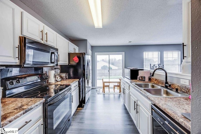 kitchen with white cabinets, sink, a wealth of natural light, and black appliances