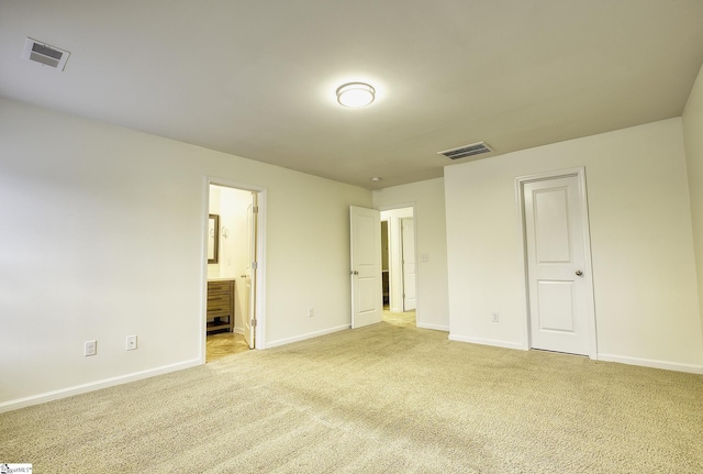 unfurnished bedroom with light colored carpet, connected bathroom, and a closet