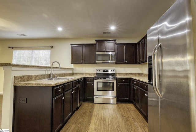 kitchen with sink, stainless steel appliances, dark brown cabinets, and light wood-type flooring