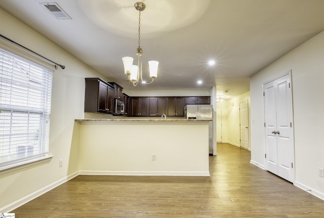 kitchen with stainless steel appliances, dark brown cabinetry, plenty of natural light, and hanging light fixtures