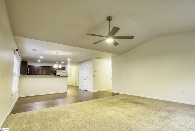 unfurnished living room with ceiling fan with notable chandelier, dark hardwood / wood-style floors, and vaulted ceiling