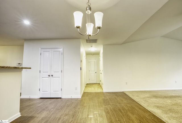 unfurnished dining area with lofted ceiling, light hardwood / wood-style floors, and a notable chandelier