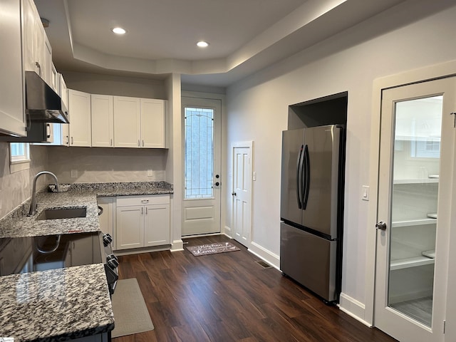 kitchen with stainless steel refrigerator, sink, dark hardwood / wood-style flooring, dark stone counters, and white cabinets