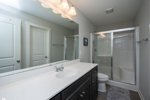 bathroom with hardwood / wood-style flooring, vanity, toilet, and a shower with shower door