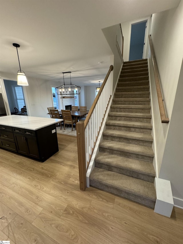 stairs with hardwood / wood-style flooring and a chandelier