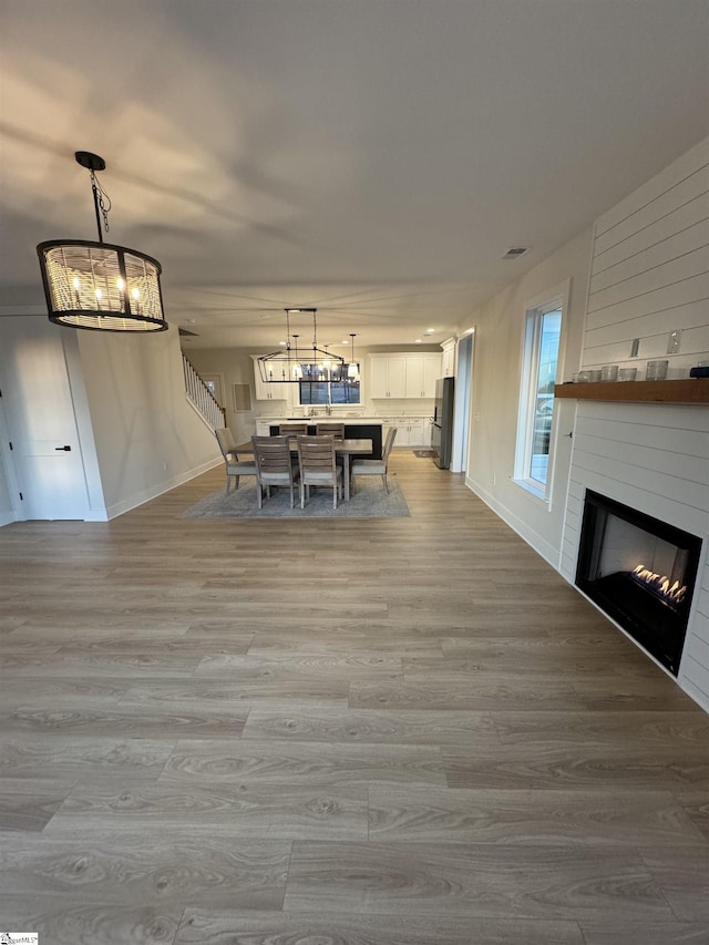 unfurnished dining area featuring light wood-type flooring, a fireplace, and an inviting chandelier