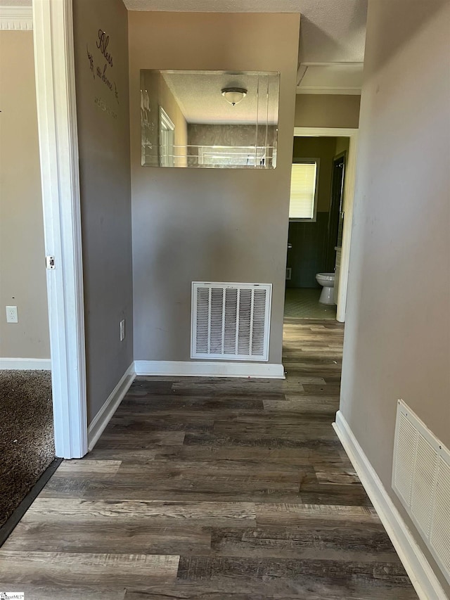 corridor with dark hardwood / wood-style flooring and a textured ceiling