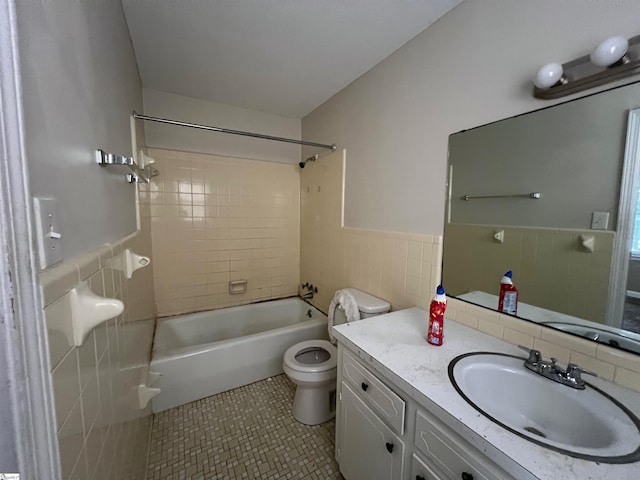 full bathroom featuring vanity, tile patterned floors, tiled shower / bath, toilet, and tile walls