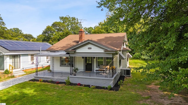 rear view of house featuring covered porch, cooling unit, and a lawn