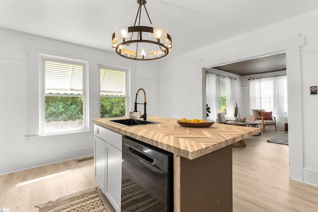 kitchen with sink, hanging light fixtures, wood counters, black dishwasher, and a center island with sink