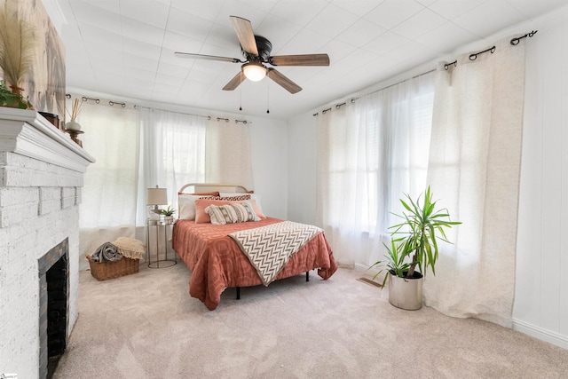 bedroom featuring a brick fireplace, ceiling fan, light carpet, and multiple windows