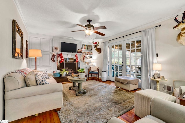 living room with ceiling fan, french doors, hardwood / wood-style flooring, a fireplace, and ornamental molding