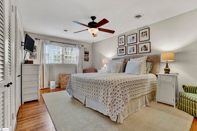 bedroom with ceiling fan, a textured ceiling, and light hardwood / wood-style flooring