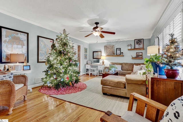 living room with hardwood / wood-style floors, ceiling fan, ornamental molding, and a textured ceiling