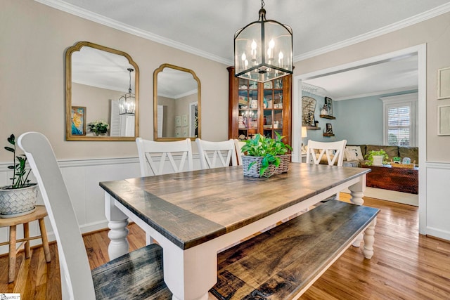 dining room with a notable chandelier, ornamental molding, and light hardwood / wood-style flooring