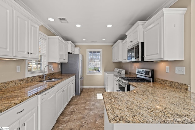 kitchen with sink, independent washer and dryer, plenty of natural light, white cabinetry, and stainless steel appliances