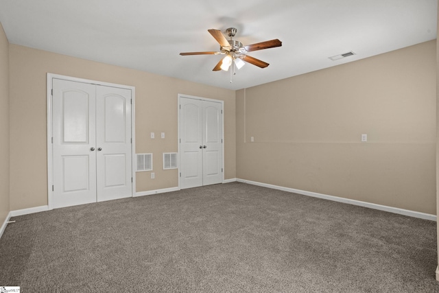 unfurnished bedroom featuring carpet, ceiling fan, and multiple closets