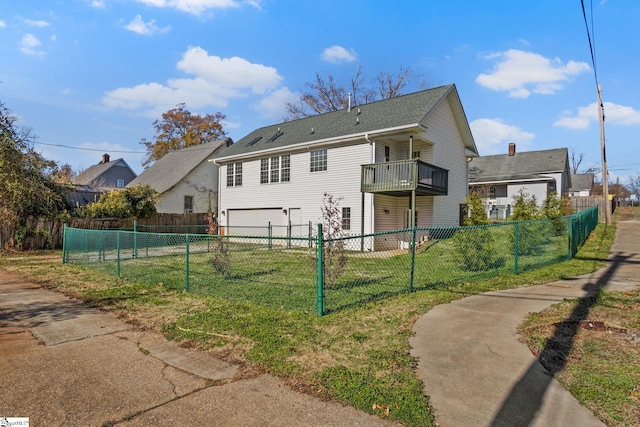 rear view of property with a garage, a balcony, and a yard