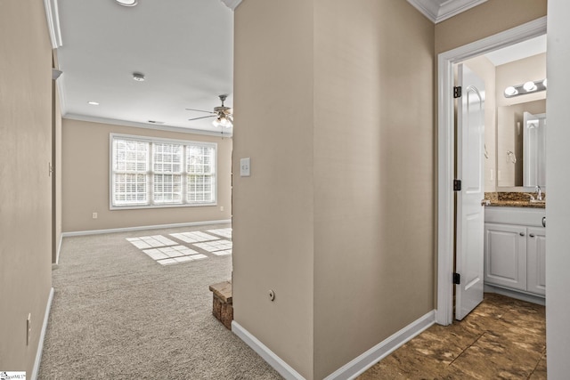 hallway with dark colored carpet, ornamental molding, and sink