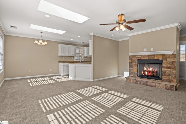 unfurnished living room with carpet flooring, ceiling fan with notable chandelier, ornamental molding, and a fireplace