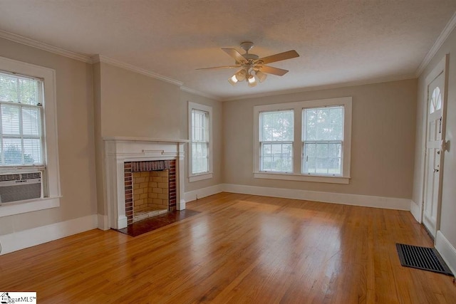 unfurnished living room featuring ceiling fan, a brick fireplace, crown molding, a textured ceiling, and light wood-type flooring