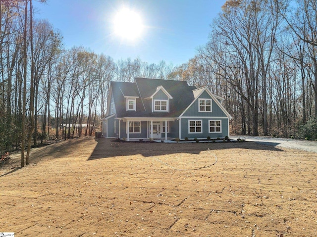 cape cod-style house featuring covered porch and a front yard