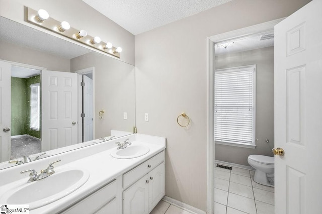 bathroom with tile patterned flooring, vanity, a healthy amount of sunlight, and a textured ceiling