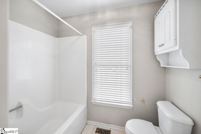 bathroom featuring bathing tub / shower combination, tile patterned flooring, a textured ceiling, and toilet