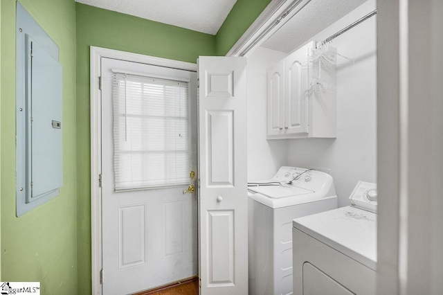 washroom featuring a textured ceiling, electric panel, cabinets, and washing machine and dryer