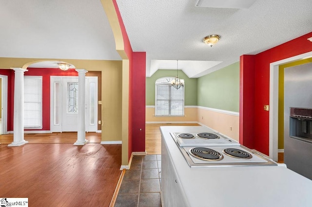 kitchen with dark wood-type flooring, a notable chandelier, pendant lighting, a textured ceiling, and lofted ceiling