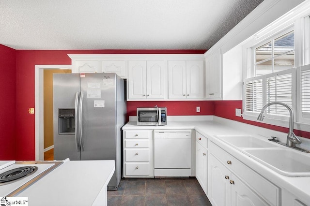 kitchen featuring sink, dark tile patterned floors, a textured ceiling, appliances with stainless steel finishes, and white cabinetry