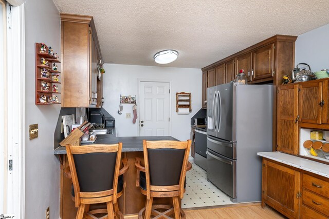 249 Monroe Bridge Rd, Honea Path, SC 29654 - kitchen featuring a textured ceiling, stainless steel appliances, light hardwood / wood-style flooring, and a breakfast bar area