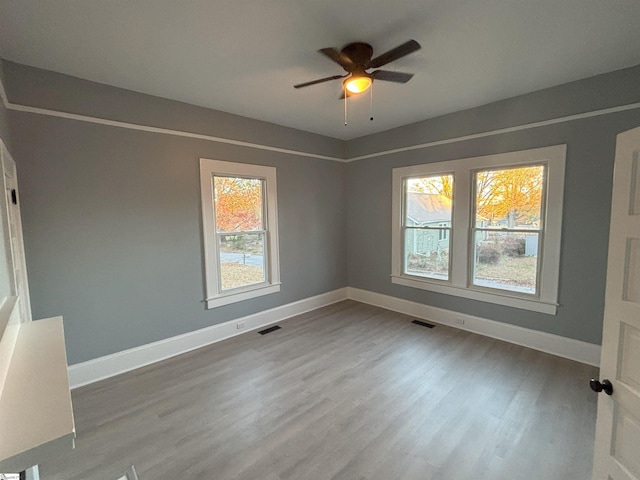 unfurnished room featuring hardwood / wood-style floors, ceiling fan, and a healthy amount of sunlight