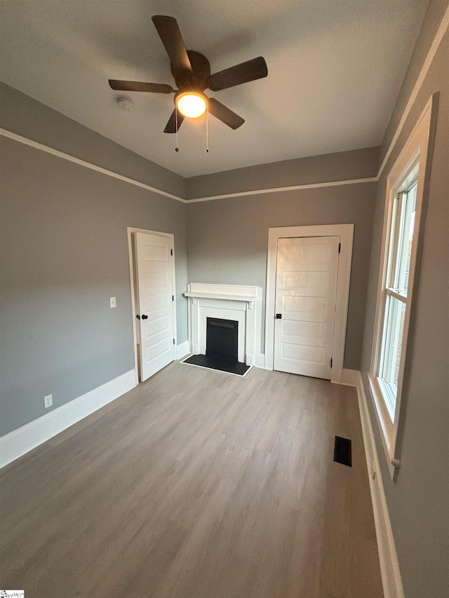 unfurnished living room with wood-type flooring, a wealth of natural light, and ceiling fan