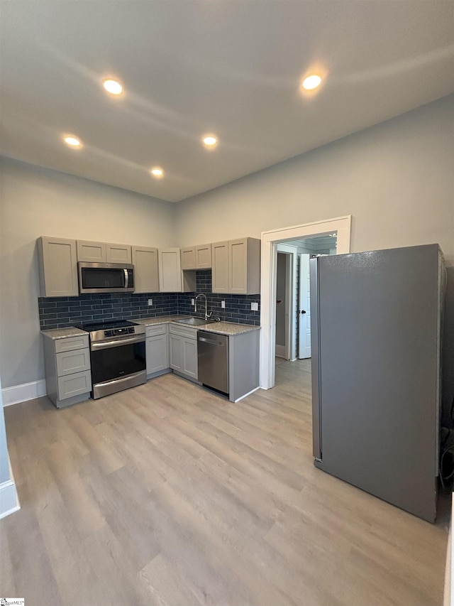 kitchen featuring sink, stainless steel appliances, tasteful backsplash, light hardwood / wood-style flooring, and gray cabinets