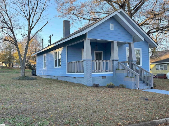 bungalow-style house featuring crawl space, a front lawn, covered porch, and a chimney