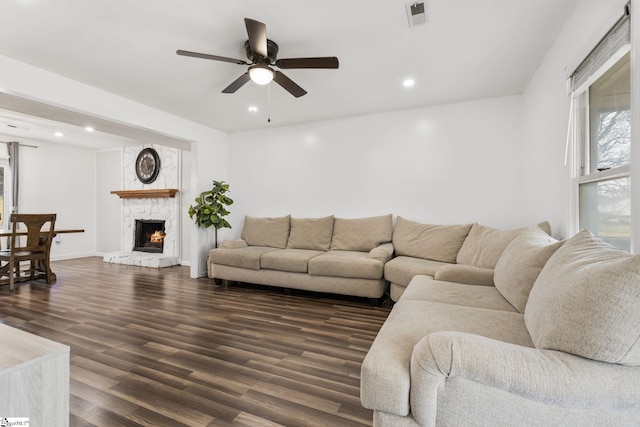 living room featuring ceiling fan, a fireplace, and dark hardwood / wood-style floors