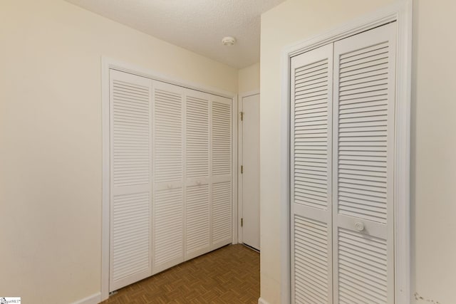 hallway featuring a textured ceiling and parquet floors