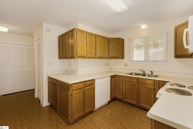 kitchen with a textured ceiling, white appliances, dark parquet floors, and sink