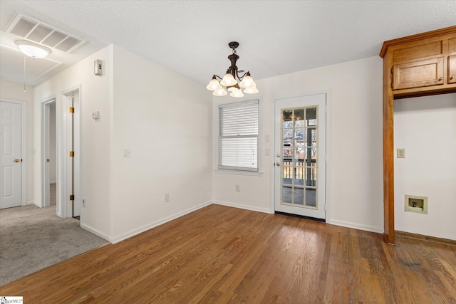 unfurnished dining area featuring a chandelier, visible vents, baseboards, and wood finished floors