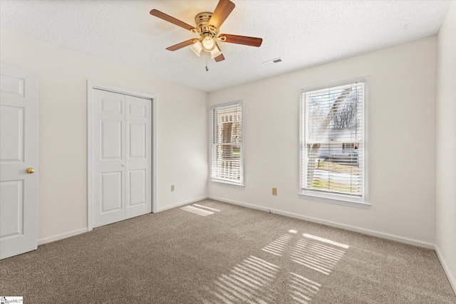 unfurnished bedroom with carpet, baseboards, visible vents, a closet, and a textured ceiling