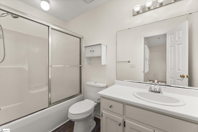 full bathroom featuring combined bath / shower with glass door, a textured ceiling, toilet, and vanity