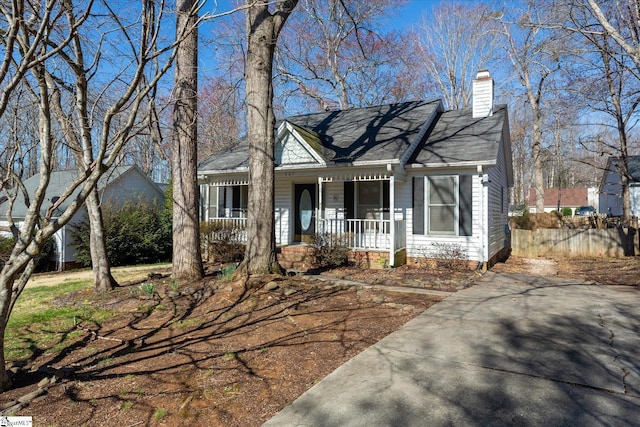 view of front facade featuring covered porch and a chimney