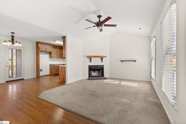 unfurnished living room featuring vaulted ceiling, a fireplace, light wood-style floors, and baseboards