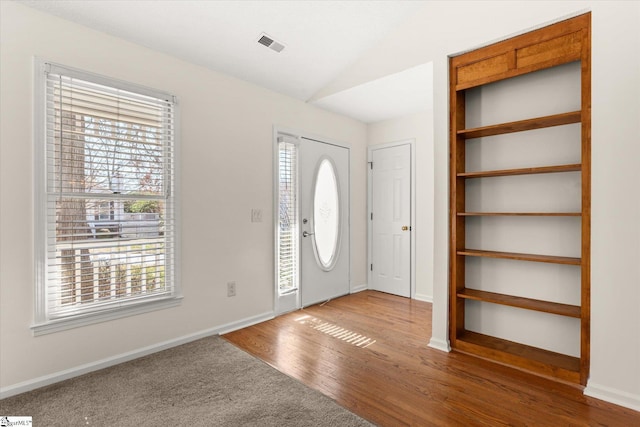 entrance foyer featuring lofted ceiling, wood finished floors, visible vents, and baseboards