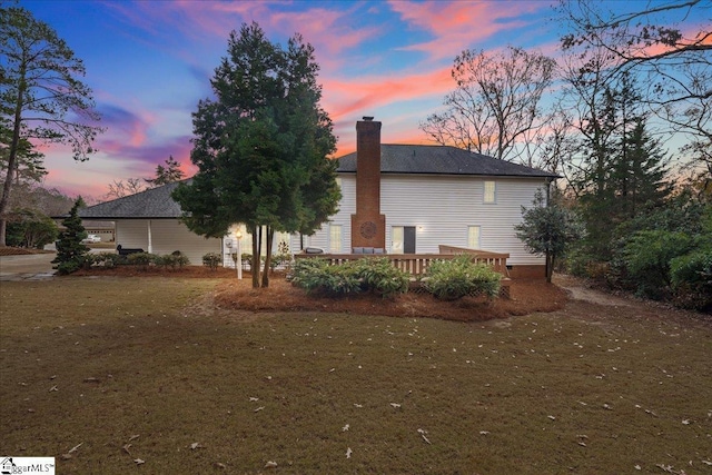 property exterior at dusk featuring a yard and a wooden deck