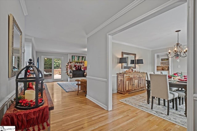 dining space featuring a chandelier, light wood-type flooring, a fireplace, and crown molding