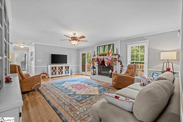 living room with crown molding, a wealth of natural light, a fireplace, and light hardwood / wood-style floors