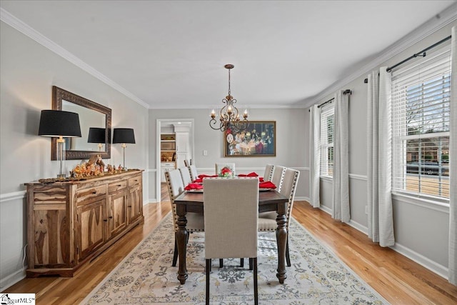 dining space with light hardwood / wood-style floors, ornamental molding, and a notable chandelier